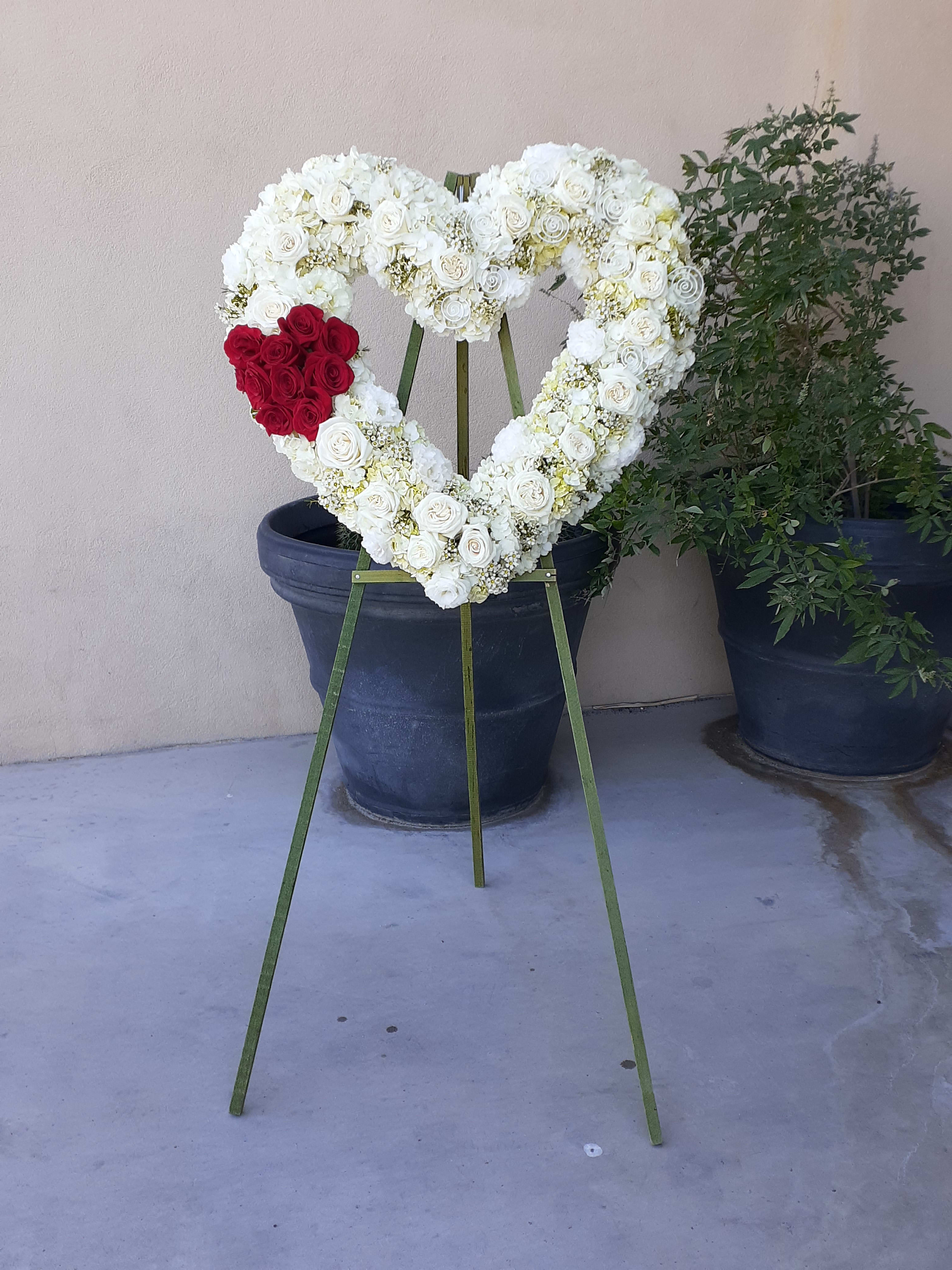 Heart-shaped white rose wreath with a red rose cluster on an easel