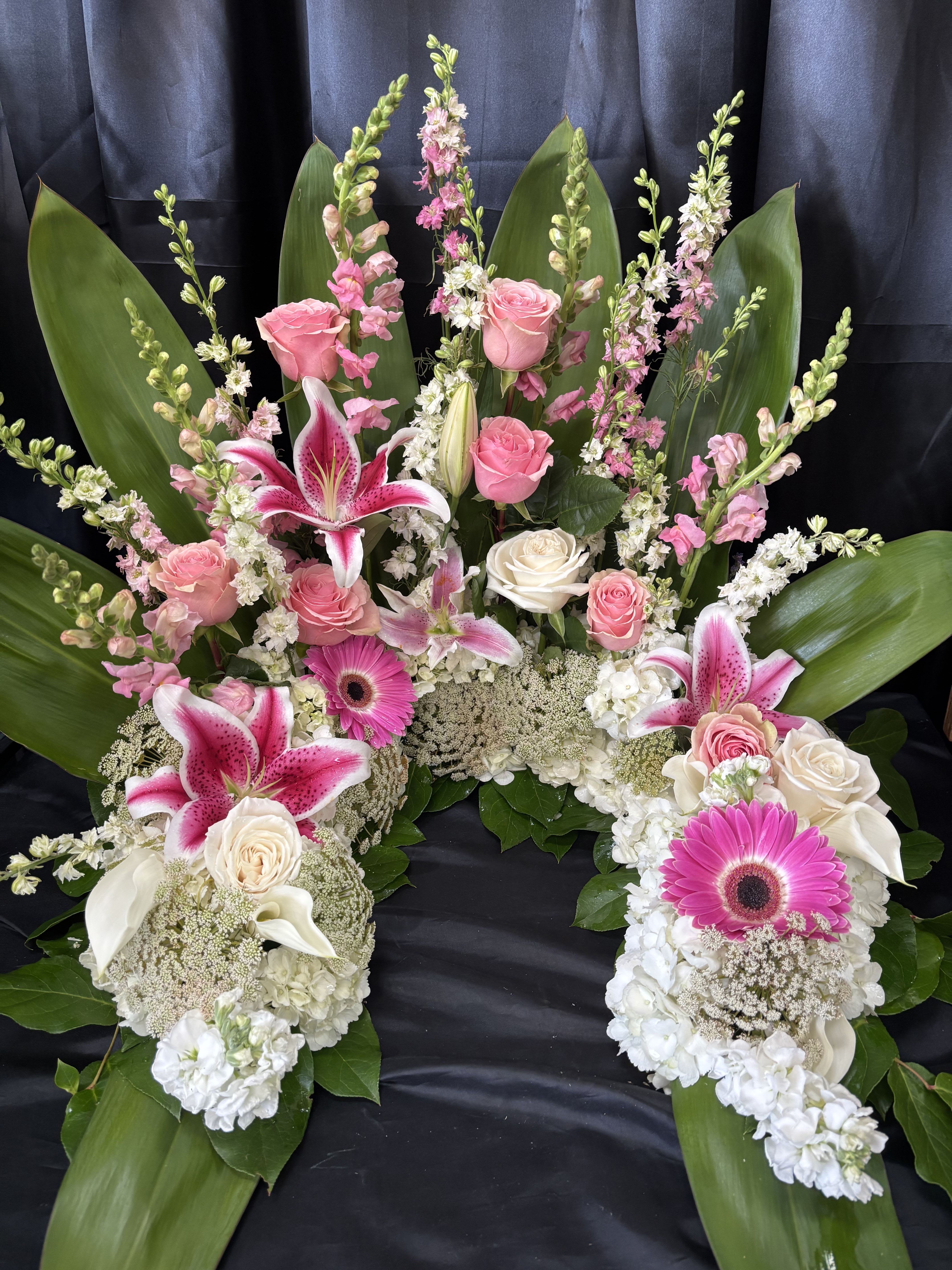 Pink and white floral funeral spray with lilies, roses, and gerbera daisies