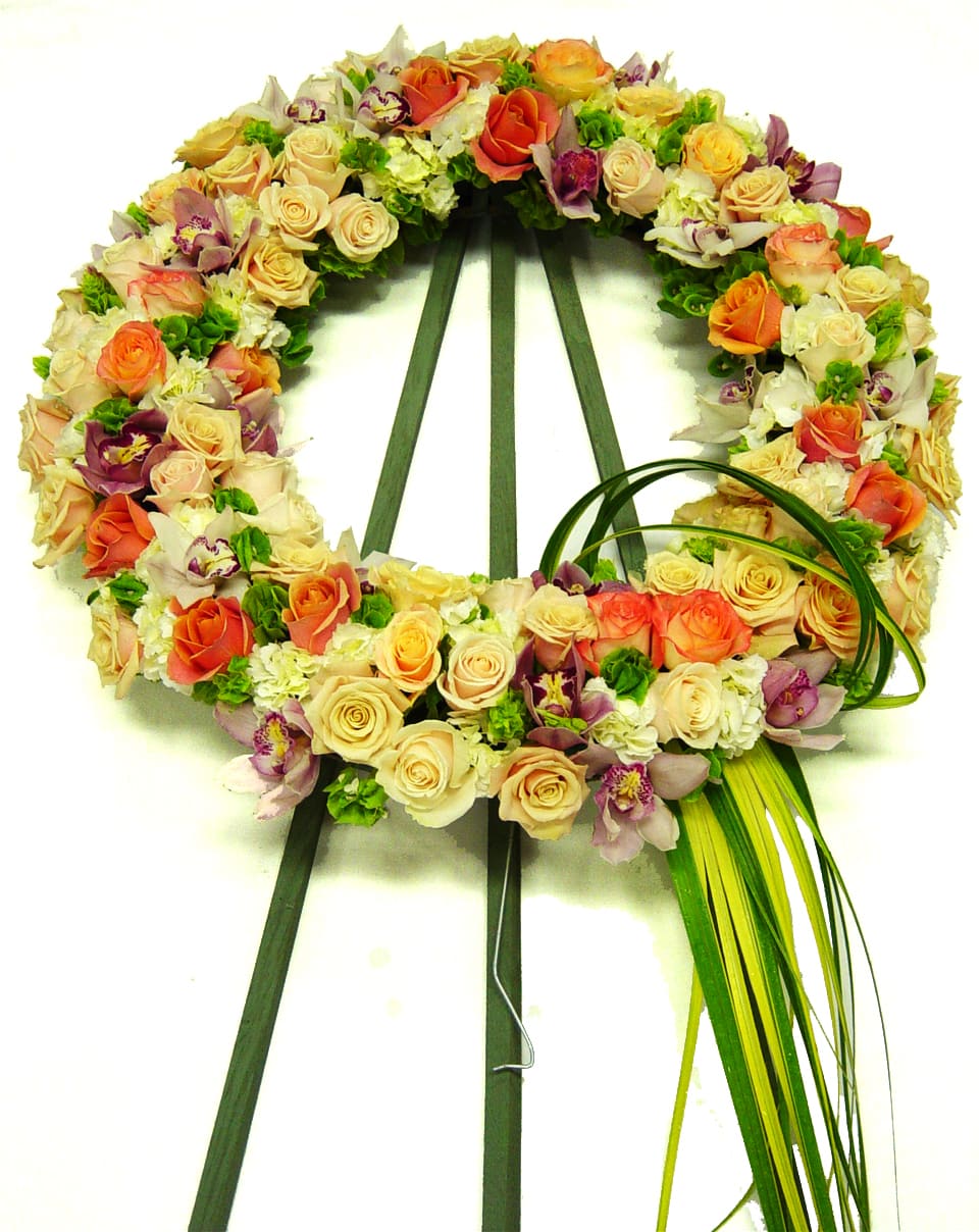 Circular floral wreath of roses and orchids on a stand