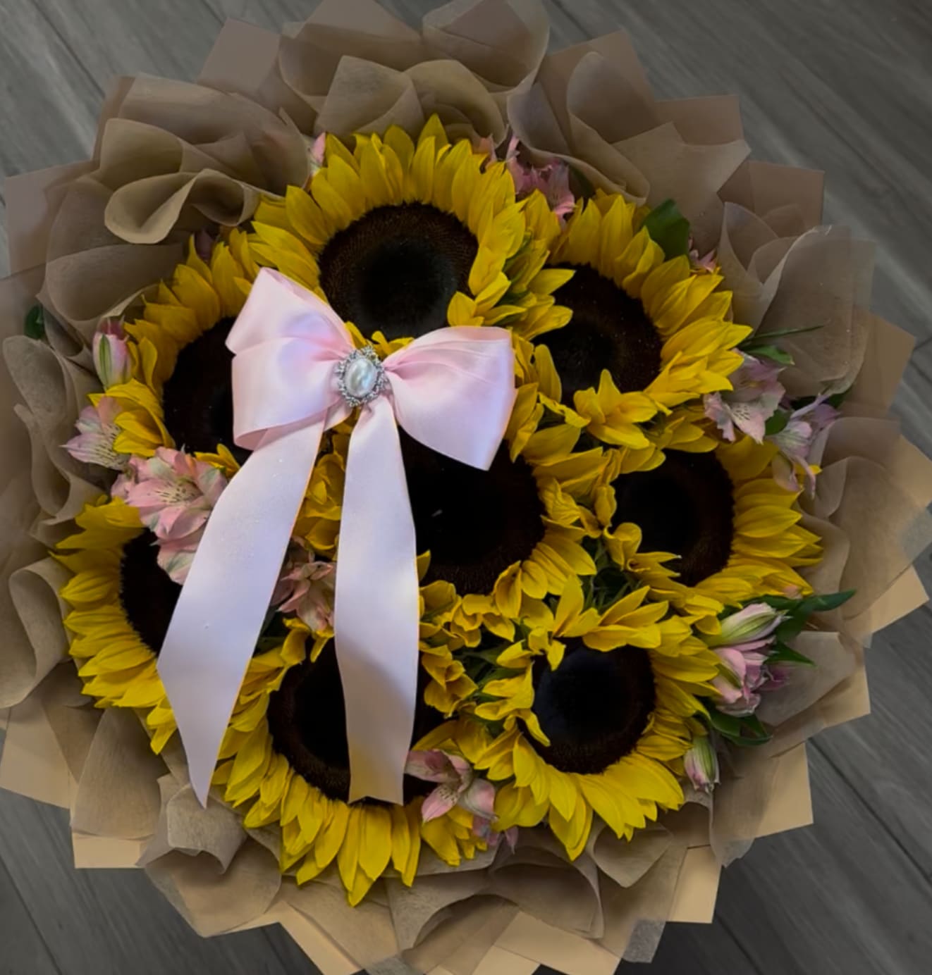 Bouquet of sunflowers with a pink ribbon and brown paper wrap