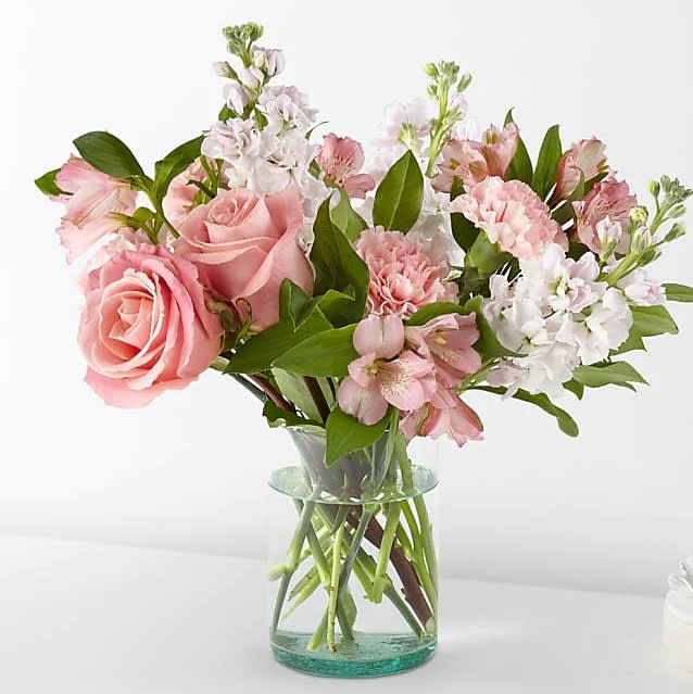 Pink roses and mixed pastel flowers in a clear glass vase