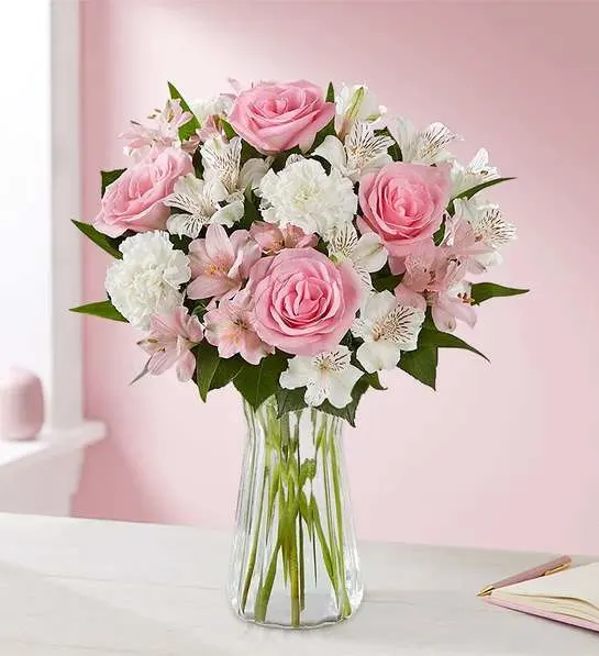 Pink roses and white flowers arranged in a clear glass vase