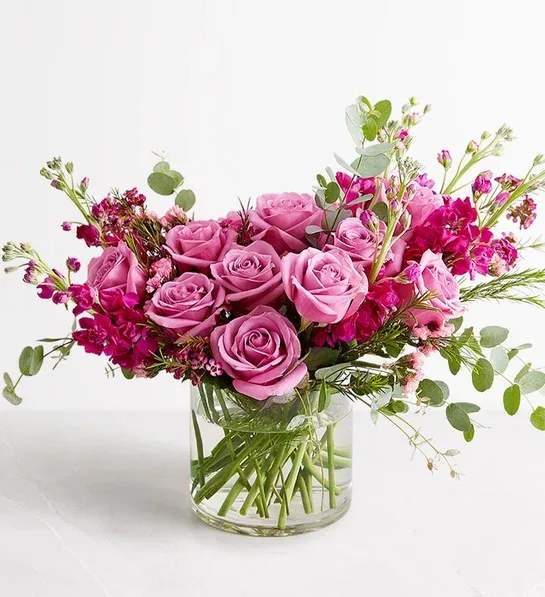 Pink roses and magenta flowers in a clear glass vase