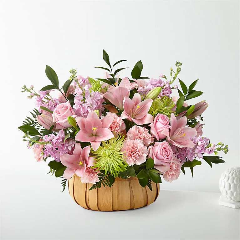 Pink lilies and roses in a woven basket arrangement