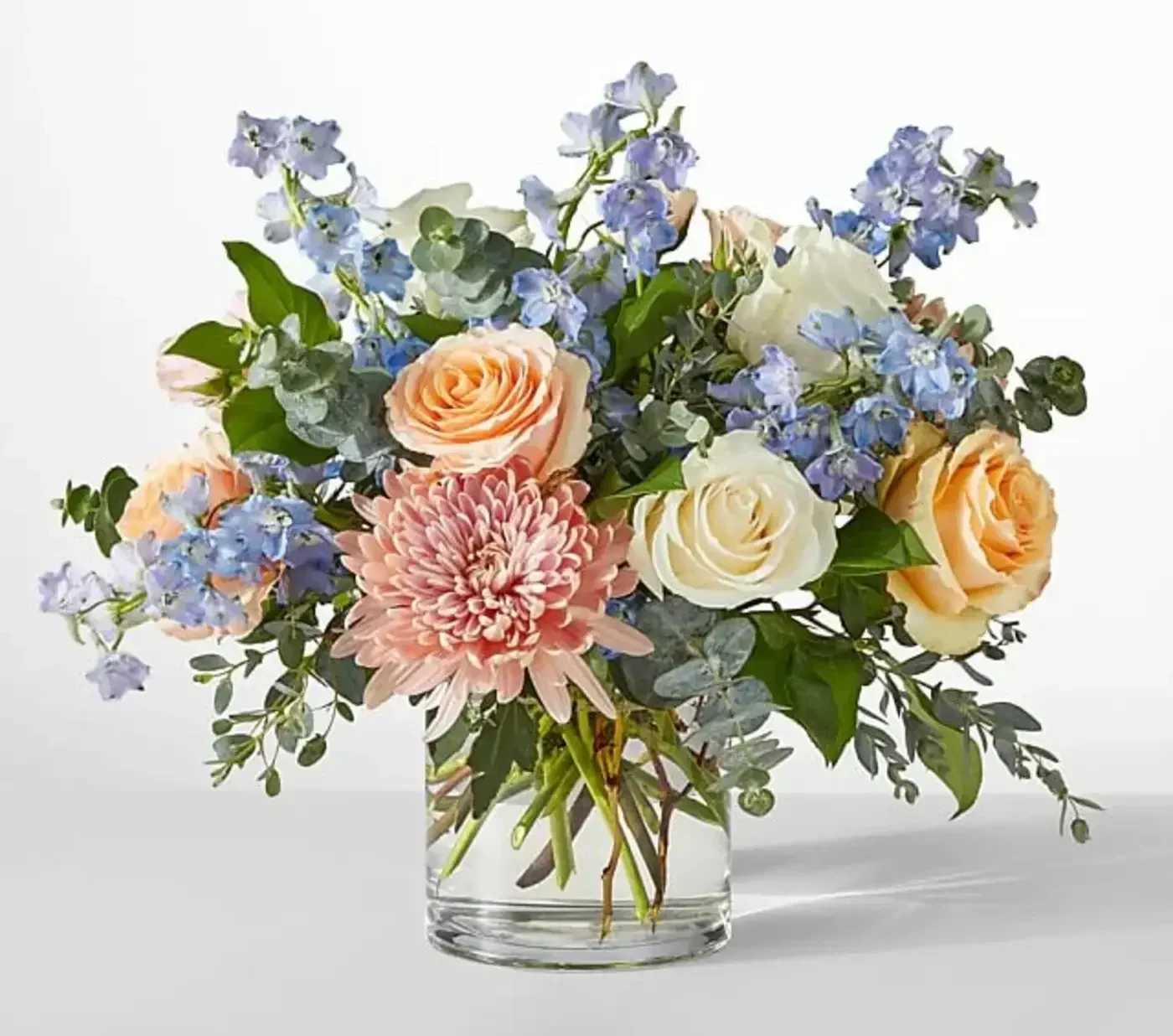 Bouquet of peach and white roses with pink chrysanthemum in a glass vase