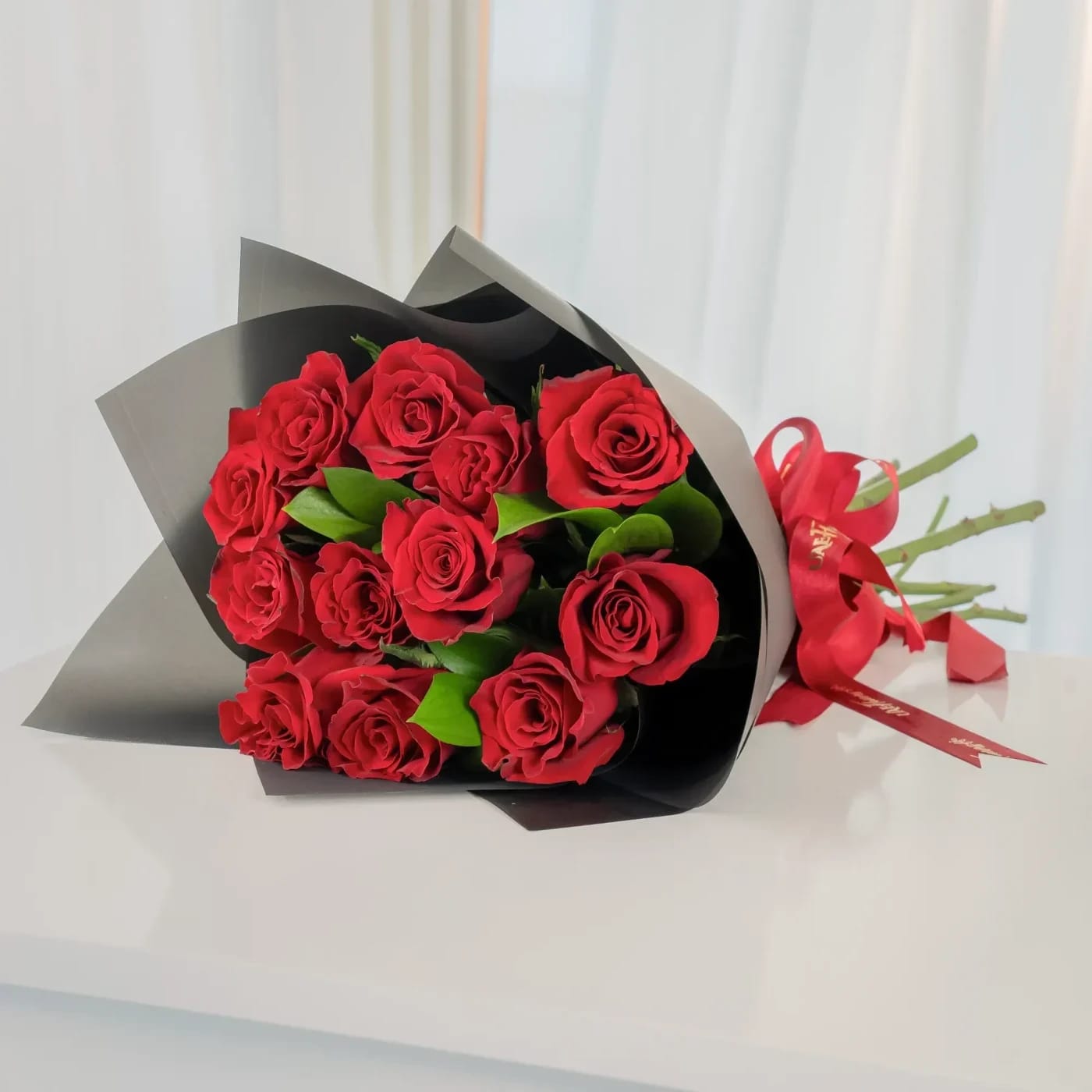 Bouquet of red roses wrapped in black paper with a red ribbon