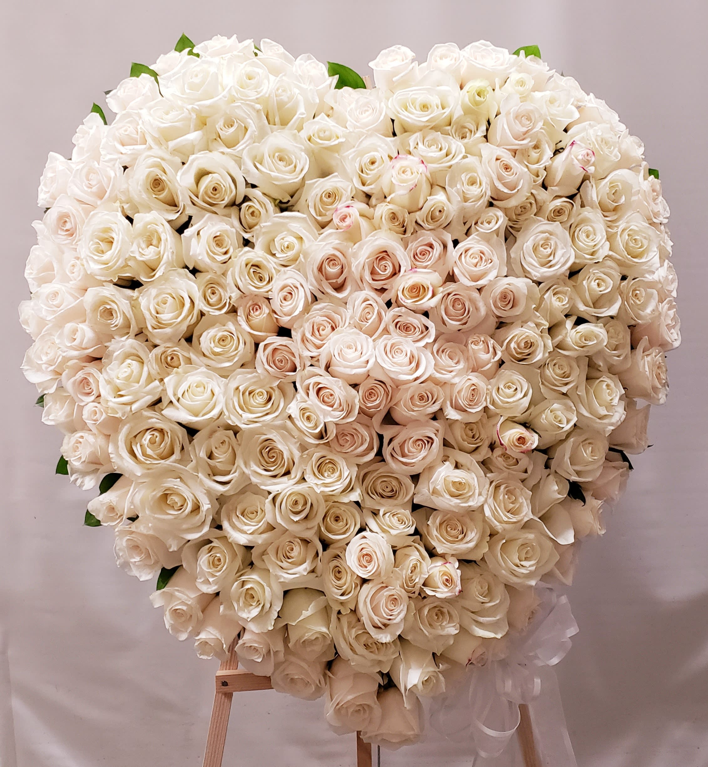 Large heart-shaped bouquet of white roses on a stand