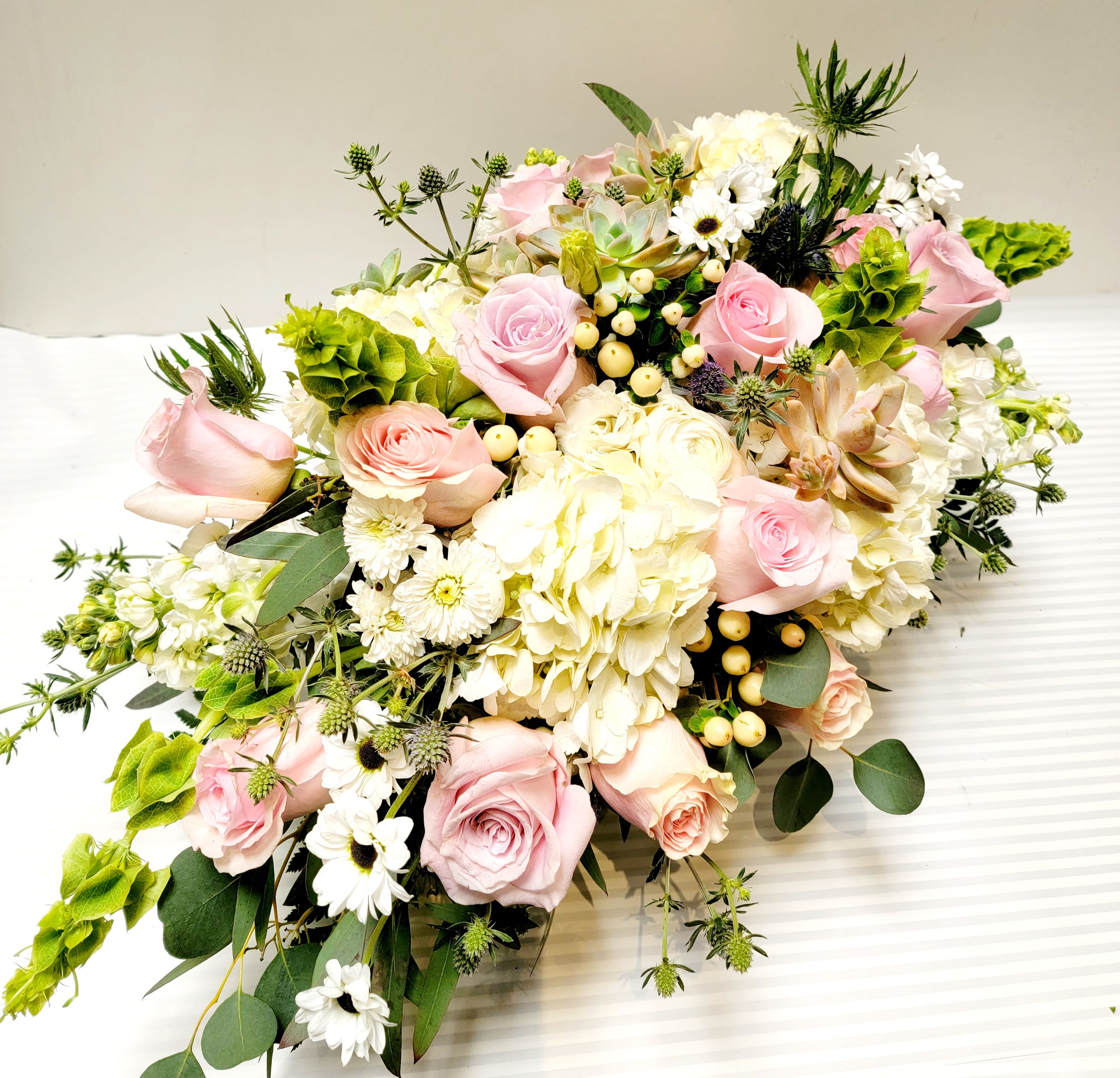 Pink roses and white hydrangeas arranged with white daisies and greenery