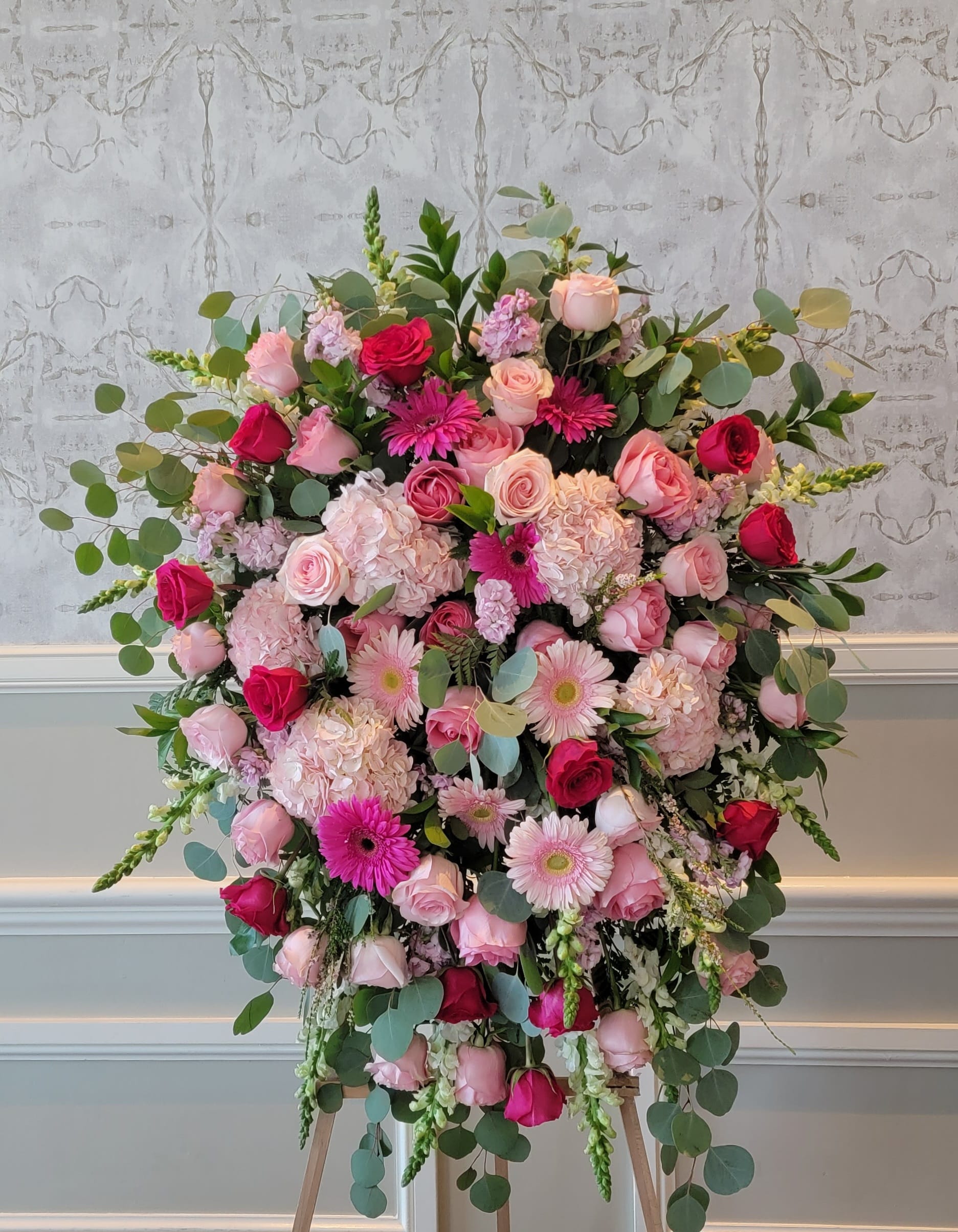 Large pink and red floral arrangement on an easel