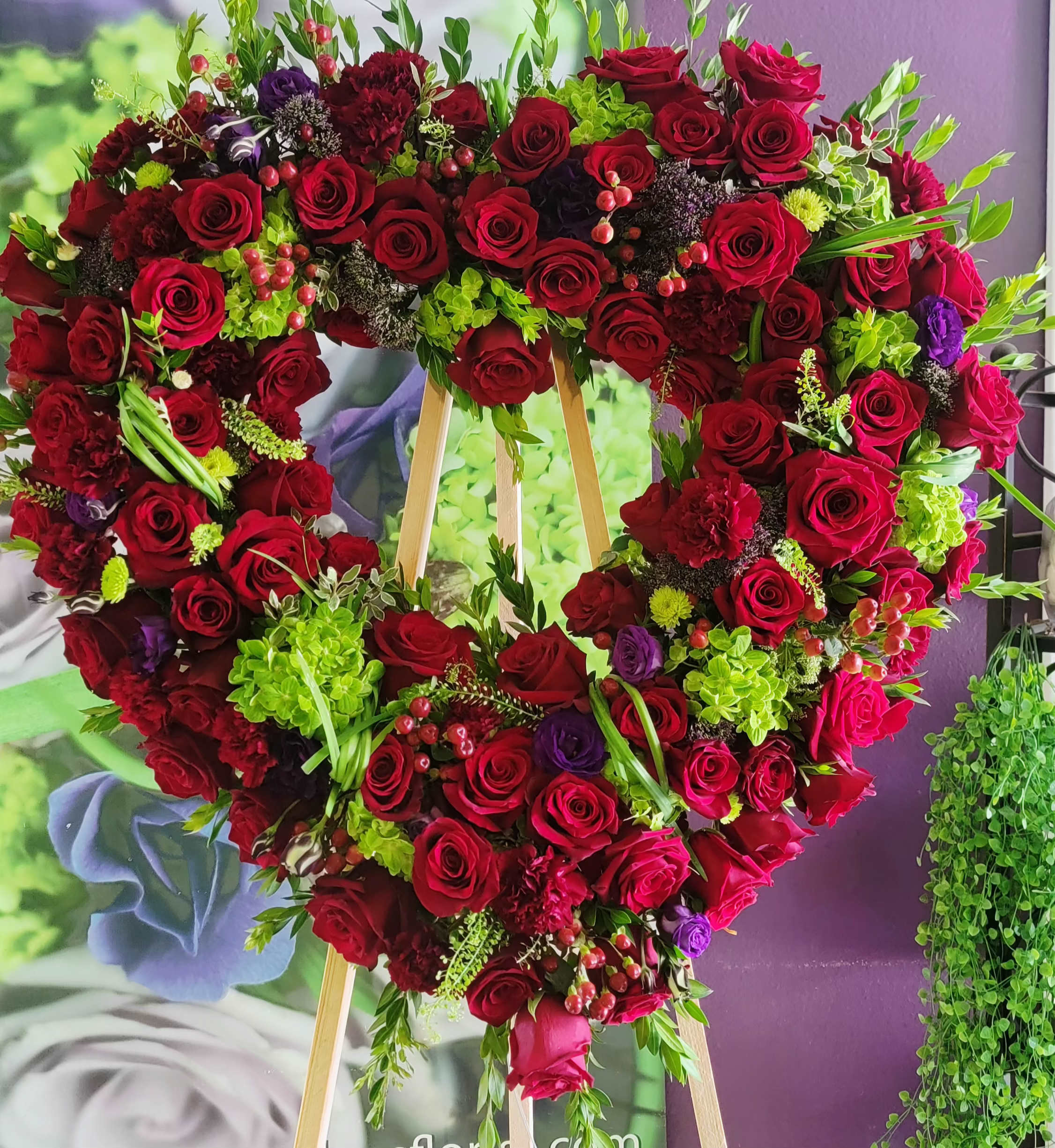 Heart-shaped floral wreath of red roses with green accents on an easel