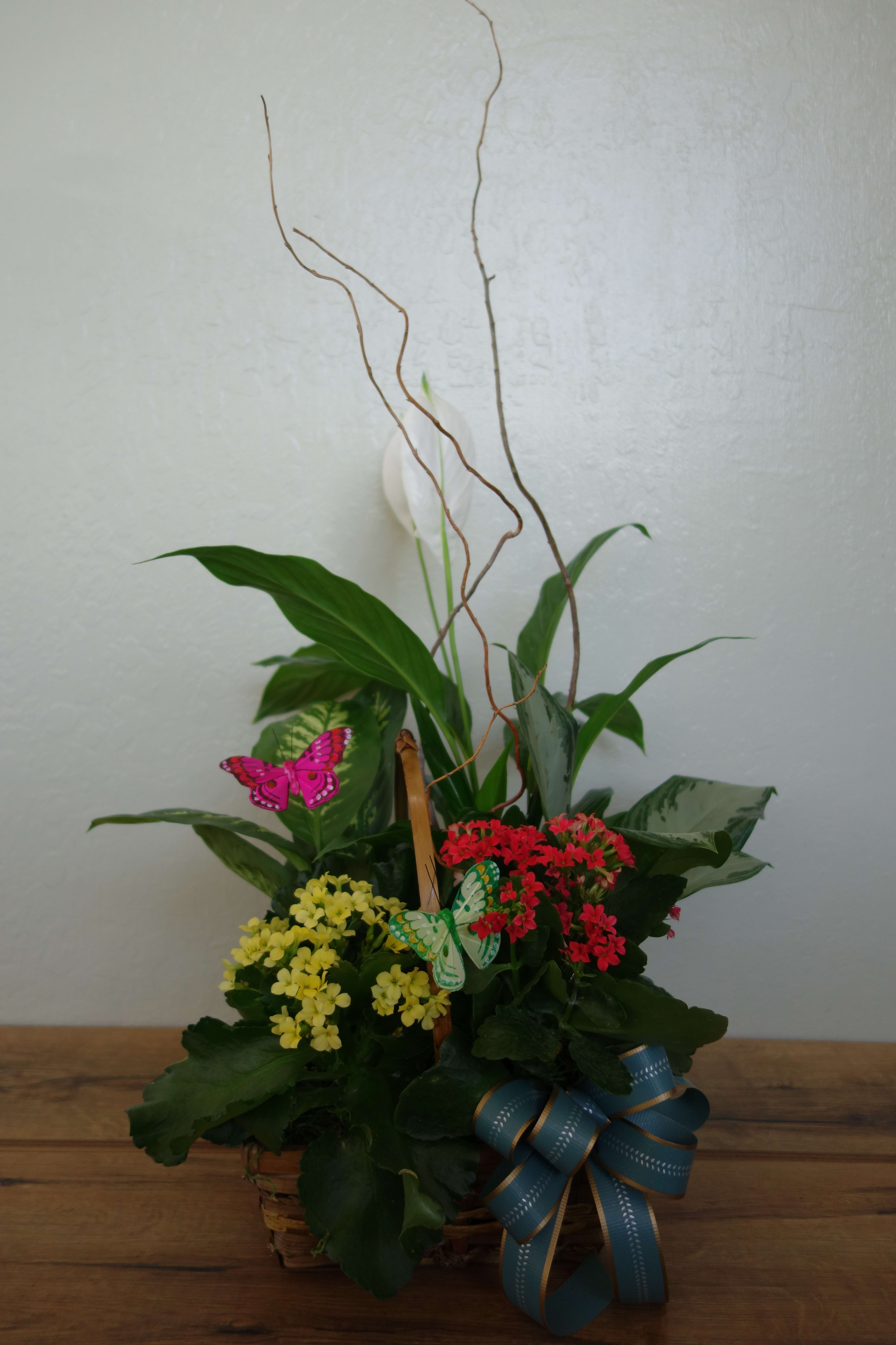 Basket arrangement with red and yellow flowers, green foliage, and butterfly picks