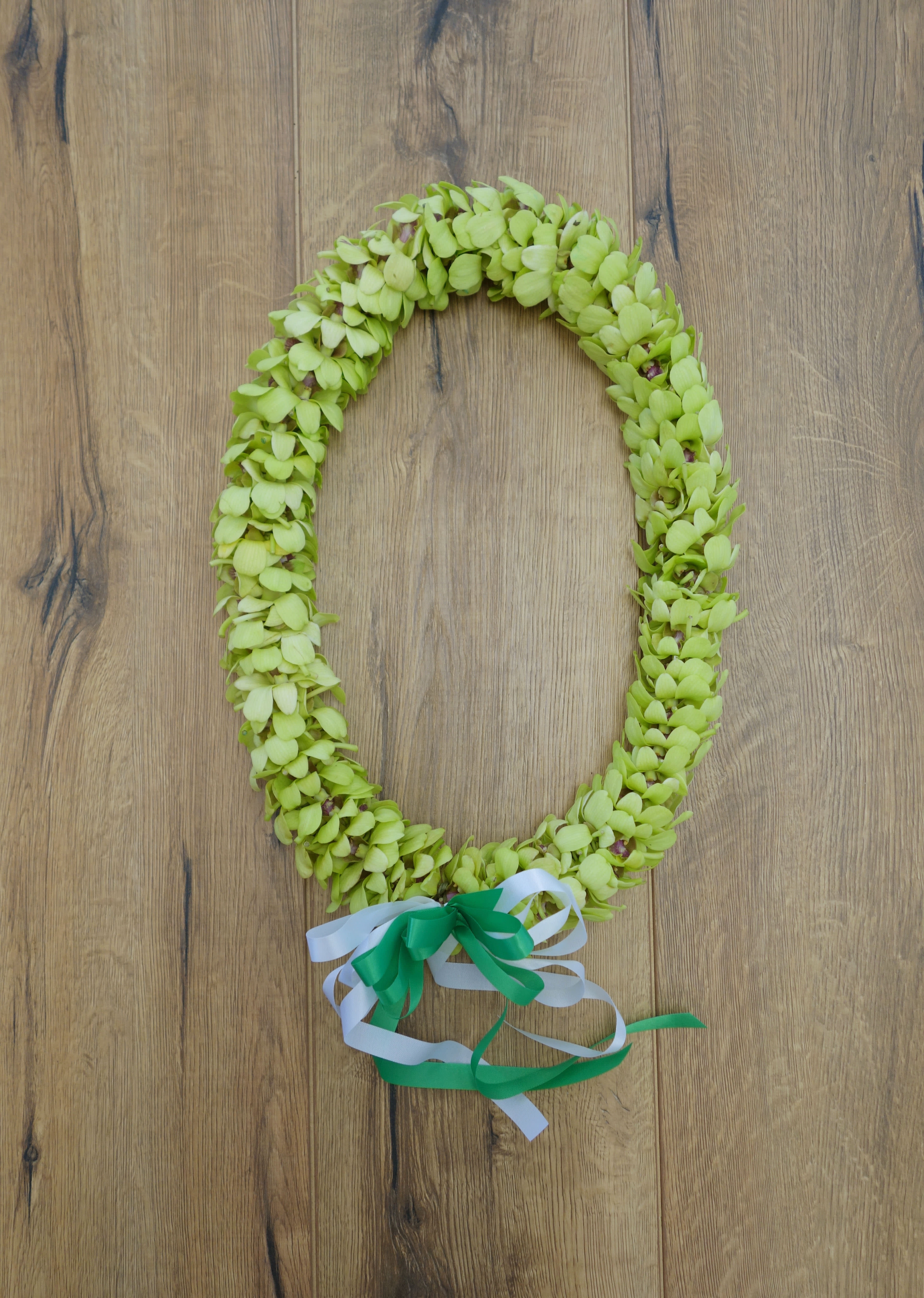Green floral lei with white and green ribbon ties