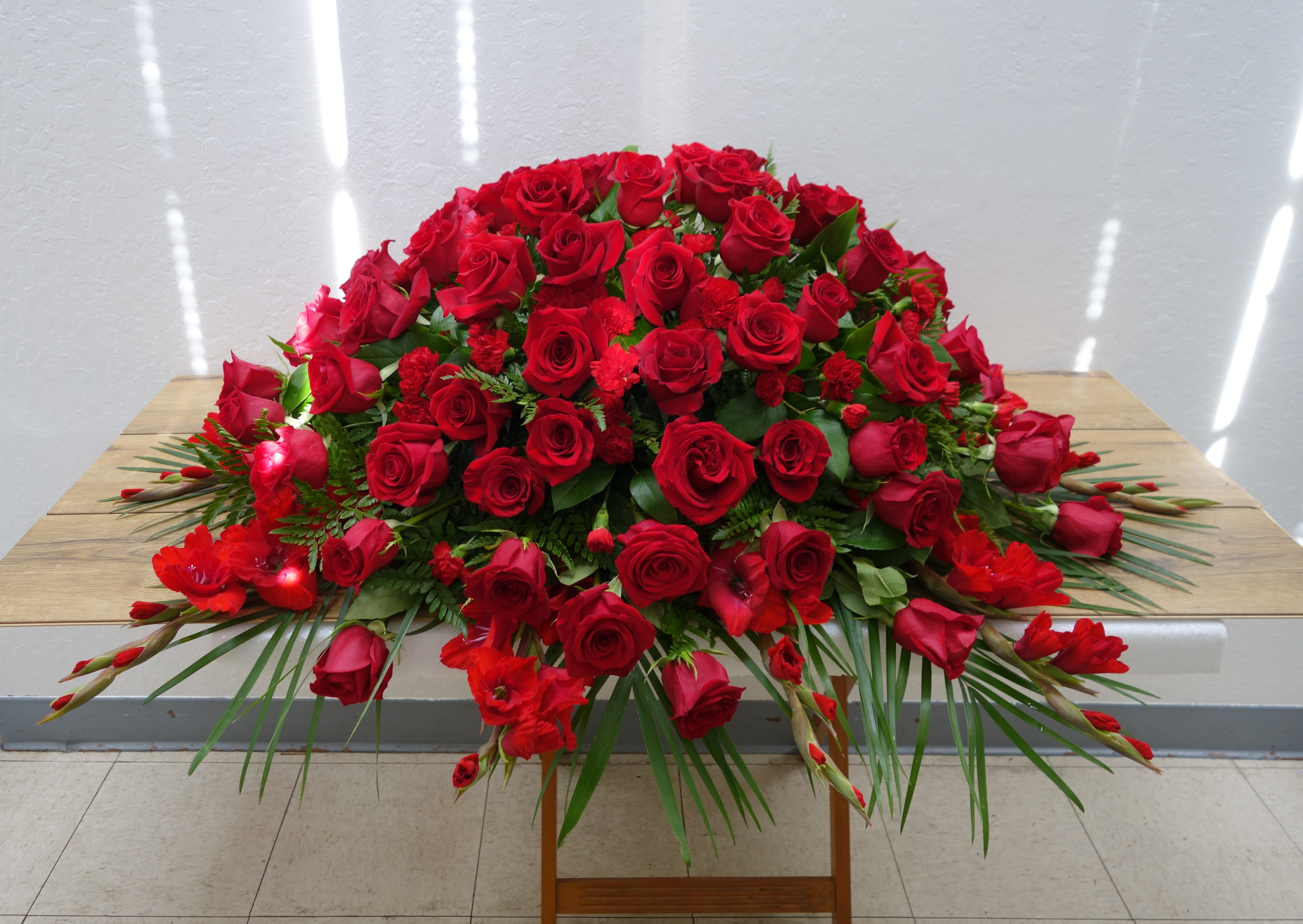 Large red rose arrangement with palm fronds on a table