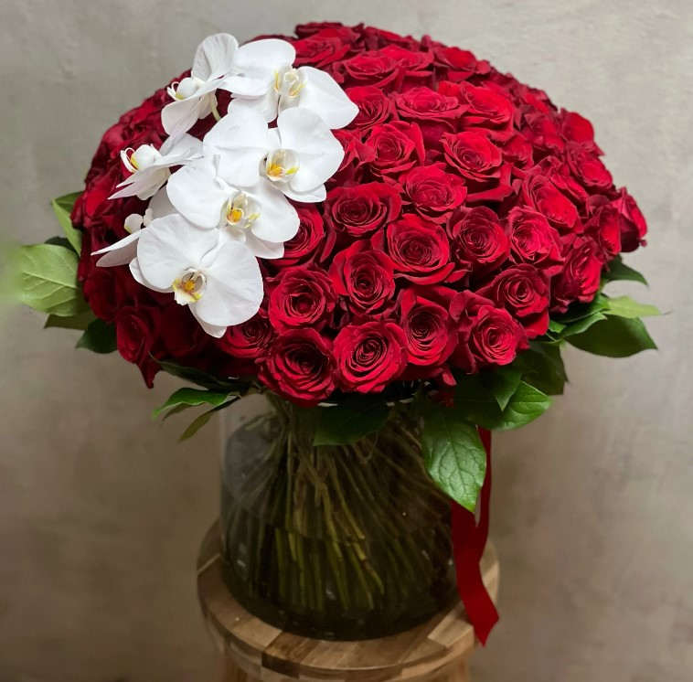 Bouquet of red roses with white orchids in a glass vase