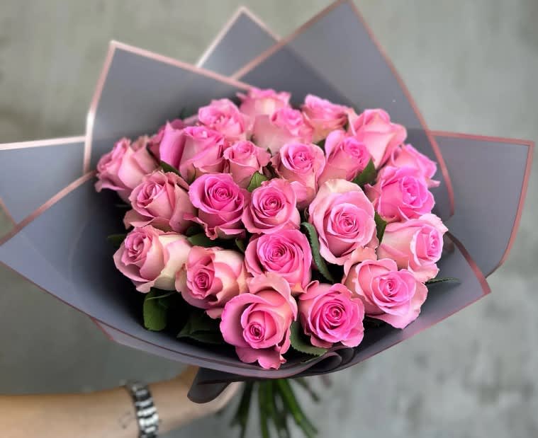 Bouquet of pink roses wrapped in dark paper