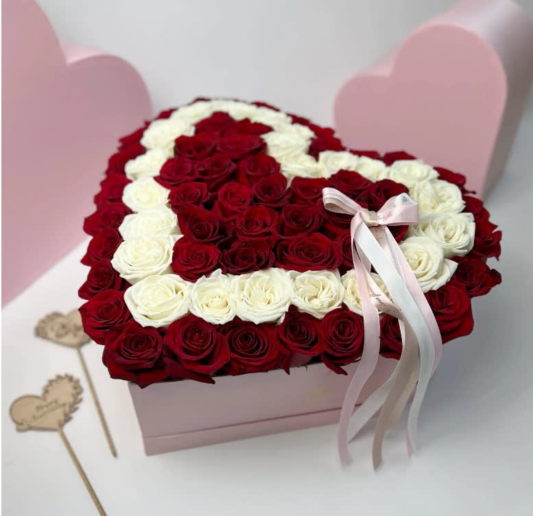 Heart-shaped box filled with red and white roses, tied with a pink ribbon