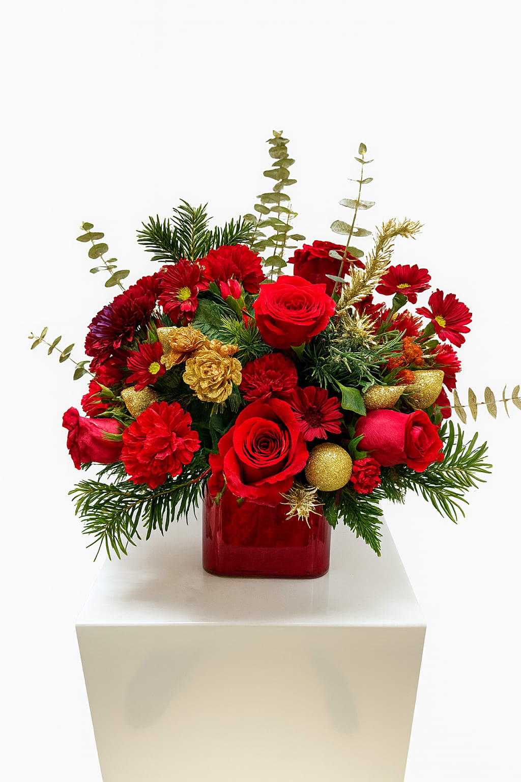 Red roses and red chrysanthemums in a red glass vase with gold accents
