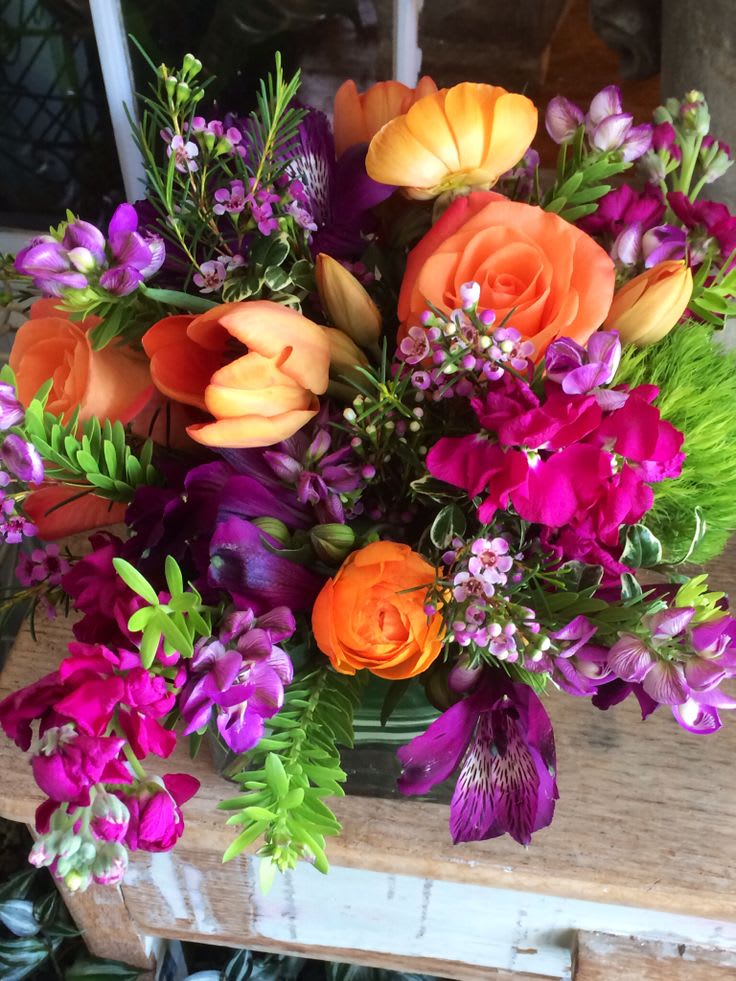 Orange and Purple  Cube - Leaf lined 5" sq cube with Cherry Brandy roses accented with a mix of purple and orange flowers accented with green trick dianthus. The mix of specialty flowers will change with the seasons.