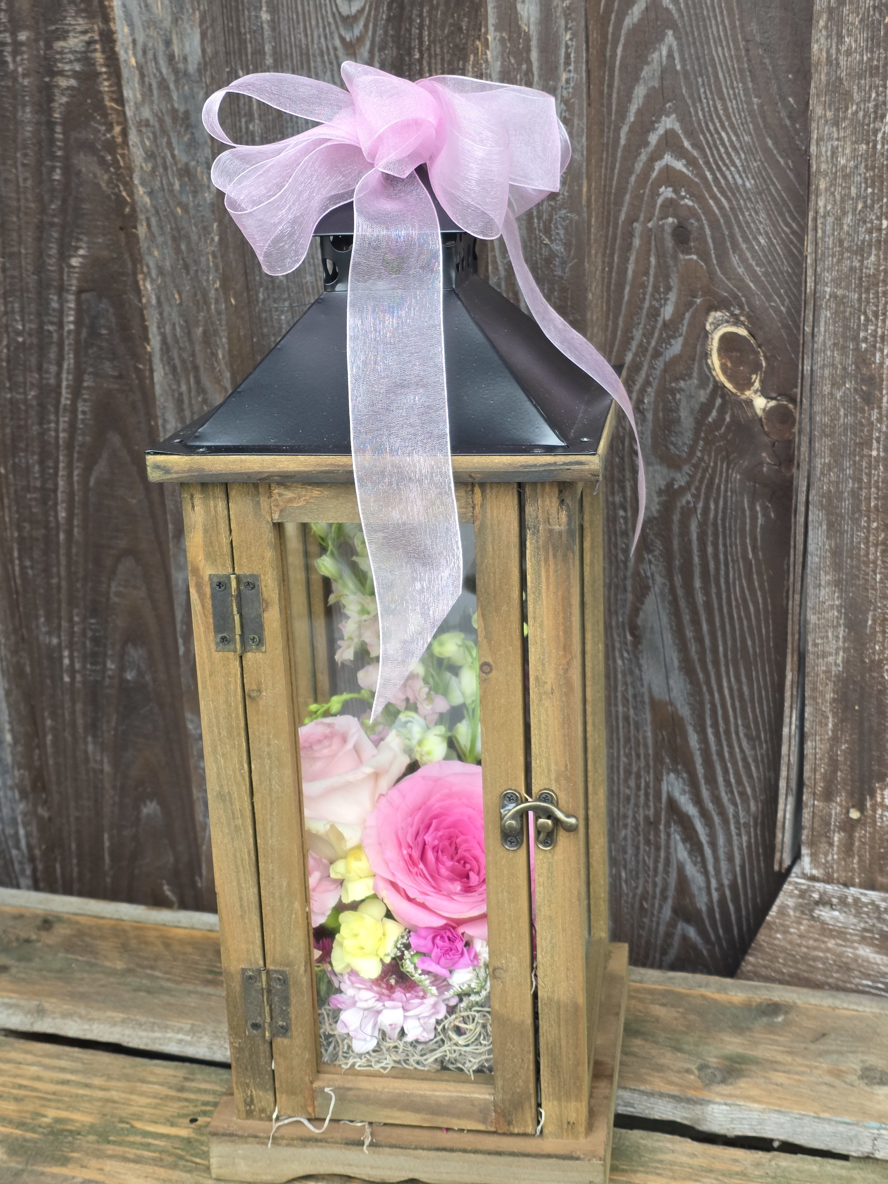 Flight of the Butterfly - This beautiful lantern is sized just right for on the table, or even on the mantle. It is filled with fresh seasonal flowers available in an assortment of colors, and includes 2 live butterflies to release.  The lantern is natural wood color and is made of wood with a metal top. It measures 19" high and is a 7.25" square base. 