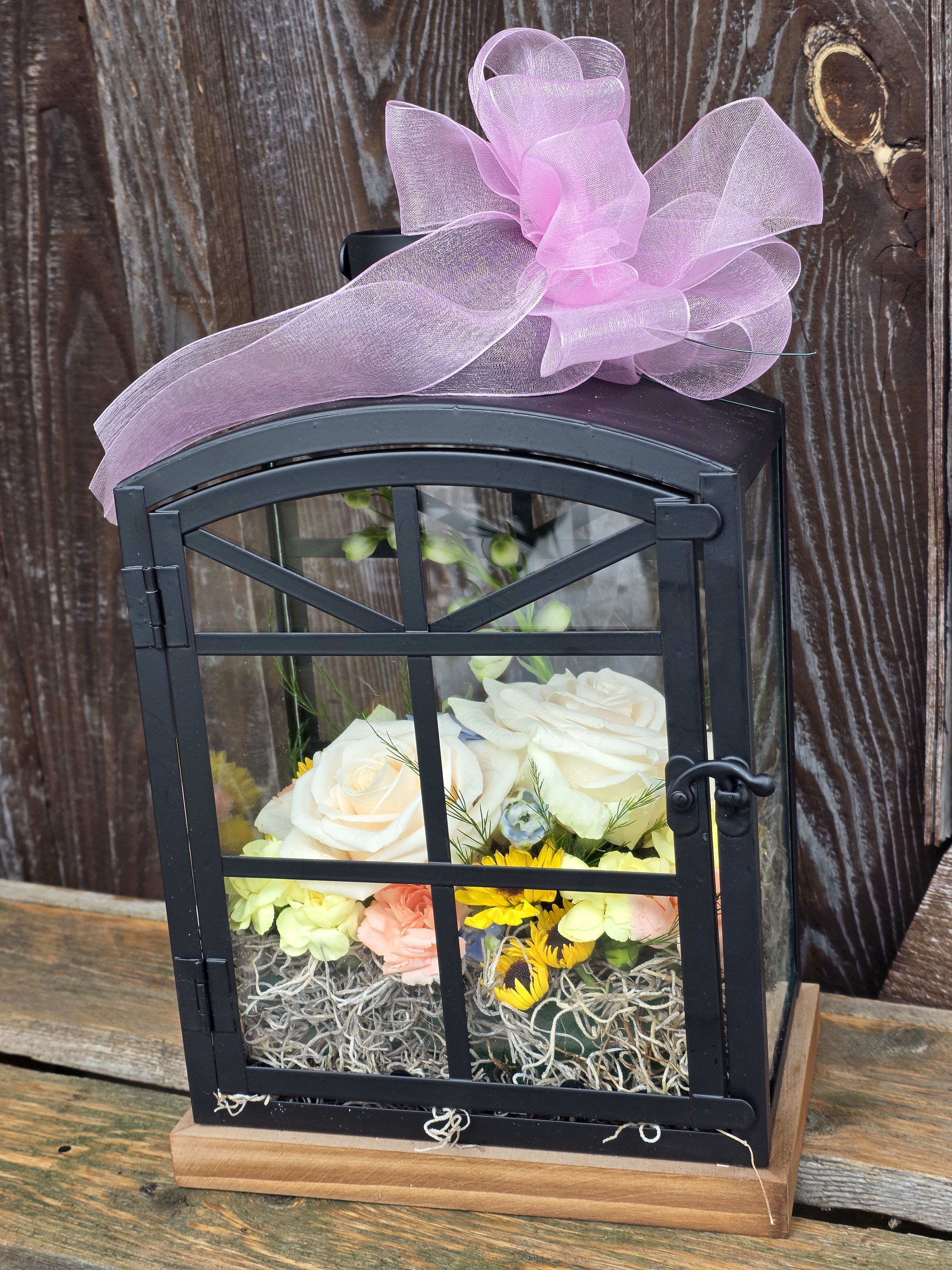 Butterfly Dream - Small - A charming lantern with a decorative arch top door on the front is filled with fresh cut flowers and live butterflies! This is a unique lantern made out of metal with a wooden base. We are happy to accommodate color requests in flowers and ribbon. Please specify when checking out. Dimensions: 12" H x 7.81" W x 5" D