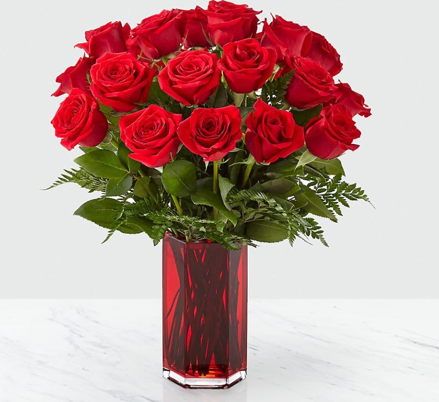 Red roses arranged in a tall red glass vase