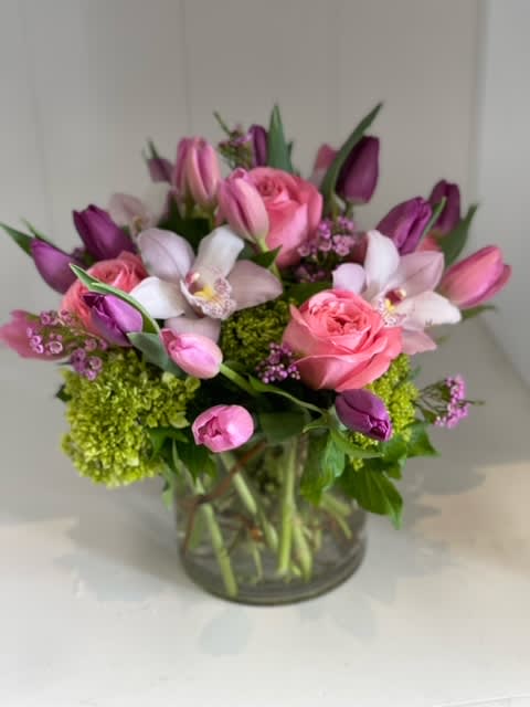 Enchanted - A luxurious blend of orchids, roses, tulips, and green hydrangeas creates a layered, textured design full of elegance and charm.  During periods of high temperatures, mini calla lilies may be used in place of tulips, as they hold up better in warm weather while maintaining the elegant look and color palette of the design.