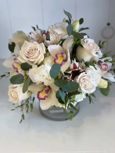 Harmony - A beautiful array of hydrangeas, roses, Cymbidium orchids, with textures of sliver dollar and dusty miller. A beautiful arrangement to celebrate and honor someone special.