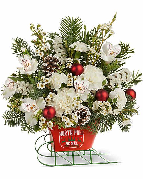 Teleflora's Santa's Sleigh Bouquet - Teleflora's Santa's Sleigh Bouquet brings a crisp winter look to the season. White blooms and evergreens are hand-arranged with festive accents in Teleflora's North Pole Sleigh Keepsake. This Christmas arrangement offers a fresh take on holiday décor with classic sleigh style.