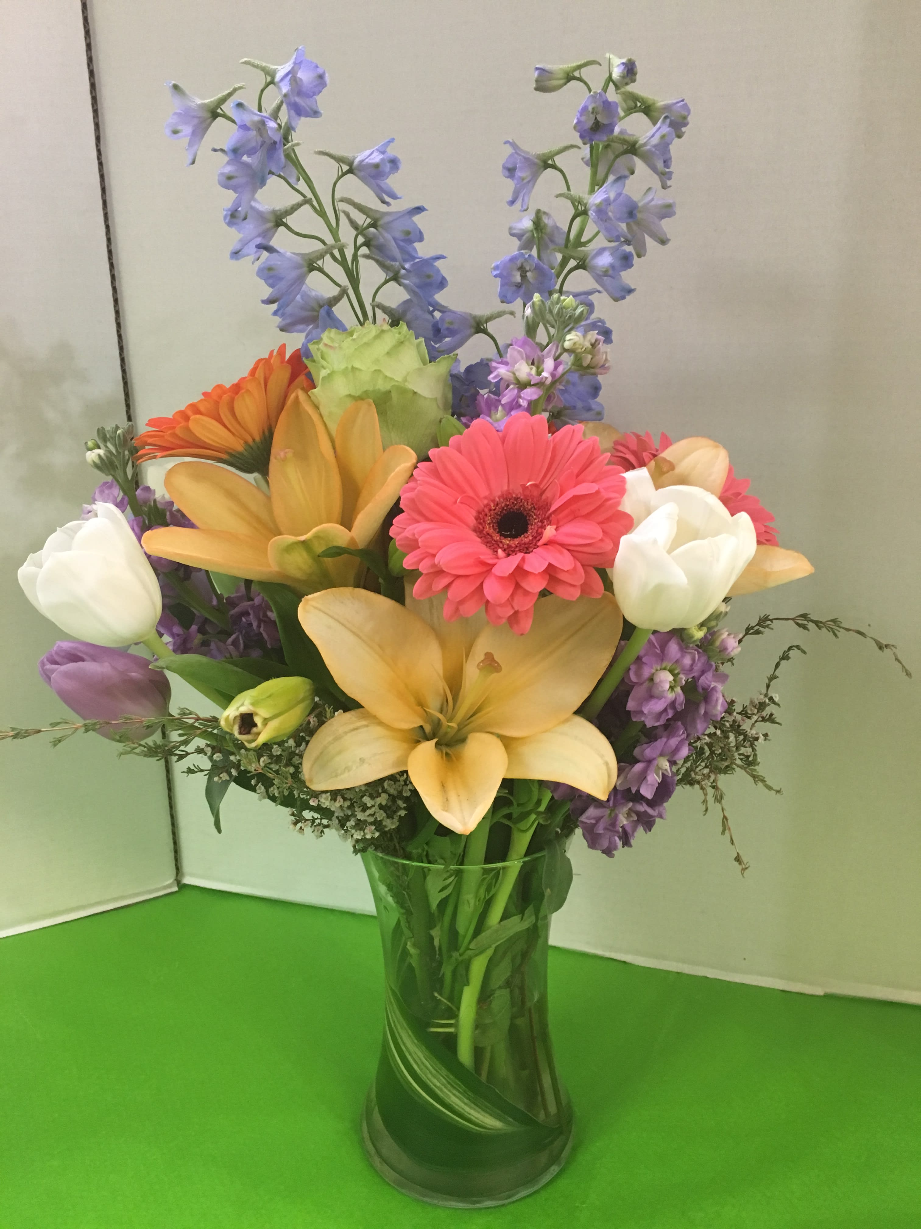 Mixed bouquet in a clear glass vase with lilies, gerbera daisies, and tulips