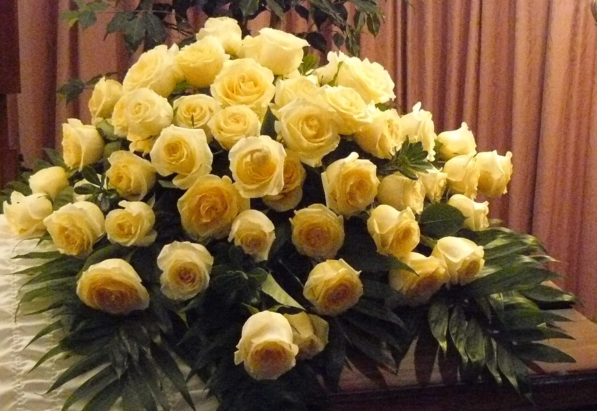 Large bouquet of pale yellow roses with dark greenery