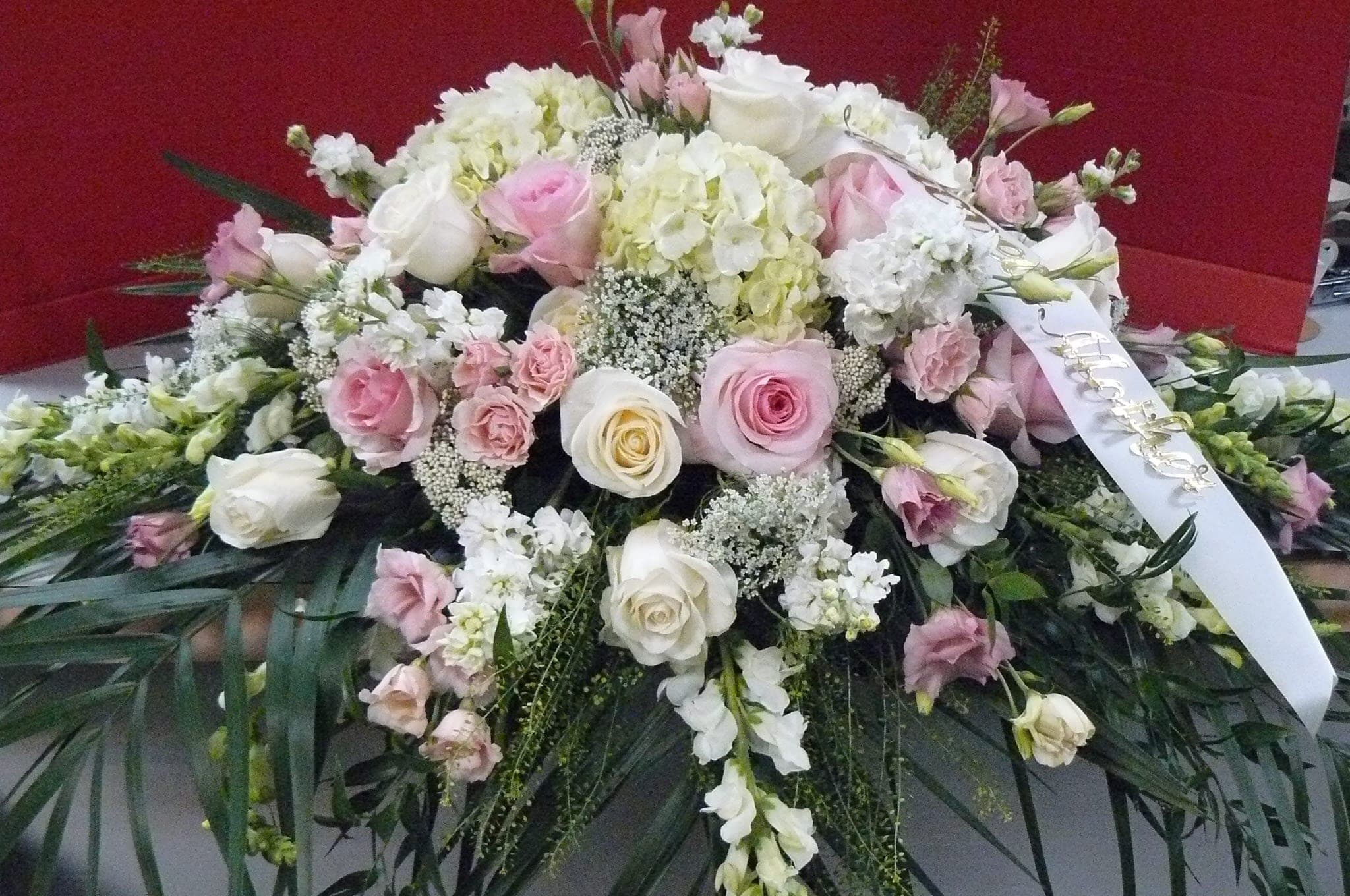 Large pink and white floral spray with a ribbon on a red background