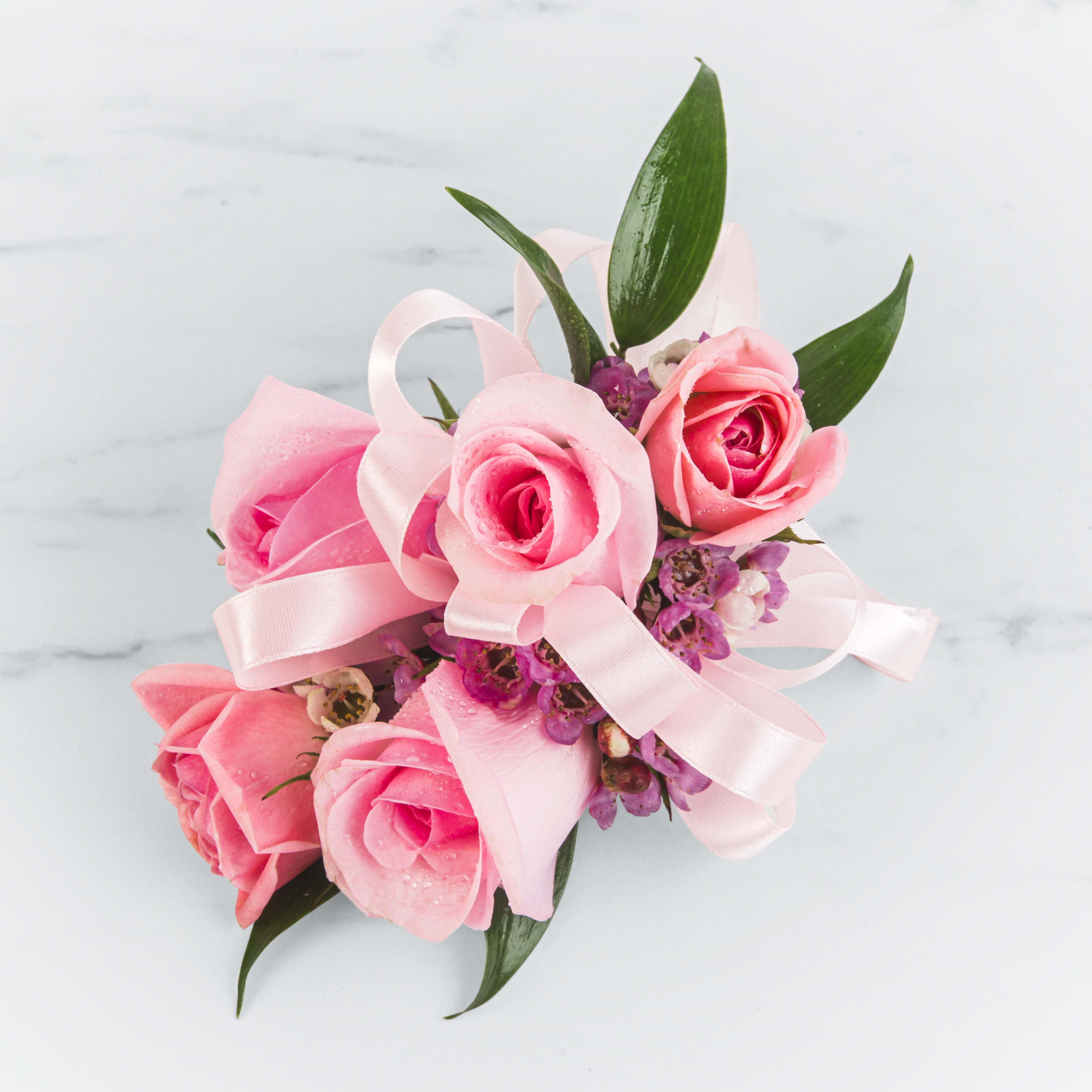 Pink rose corsage with ribbon and small purple flowers