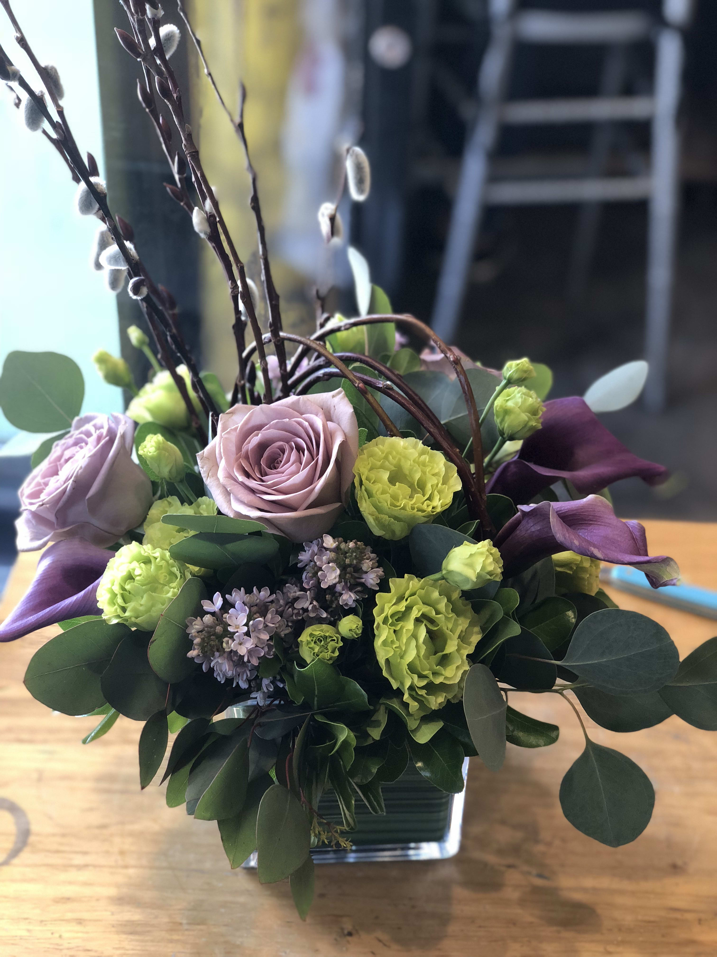 Lavender roses and green carnations in a square glass vase