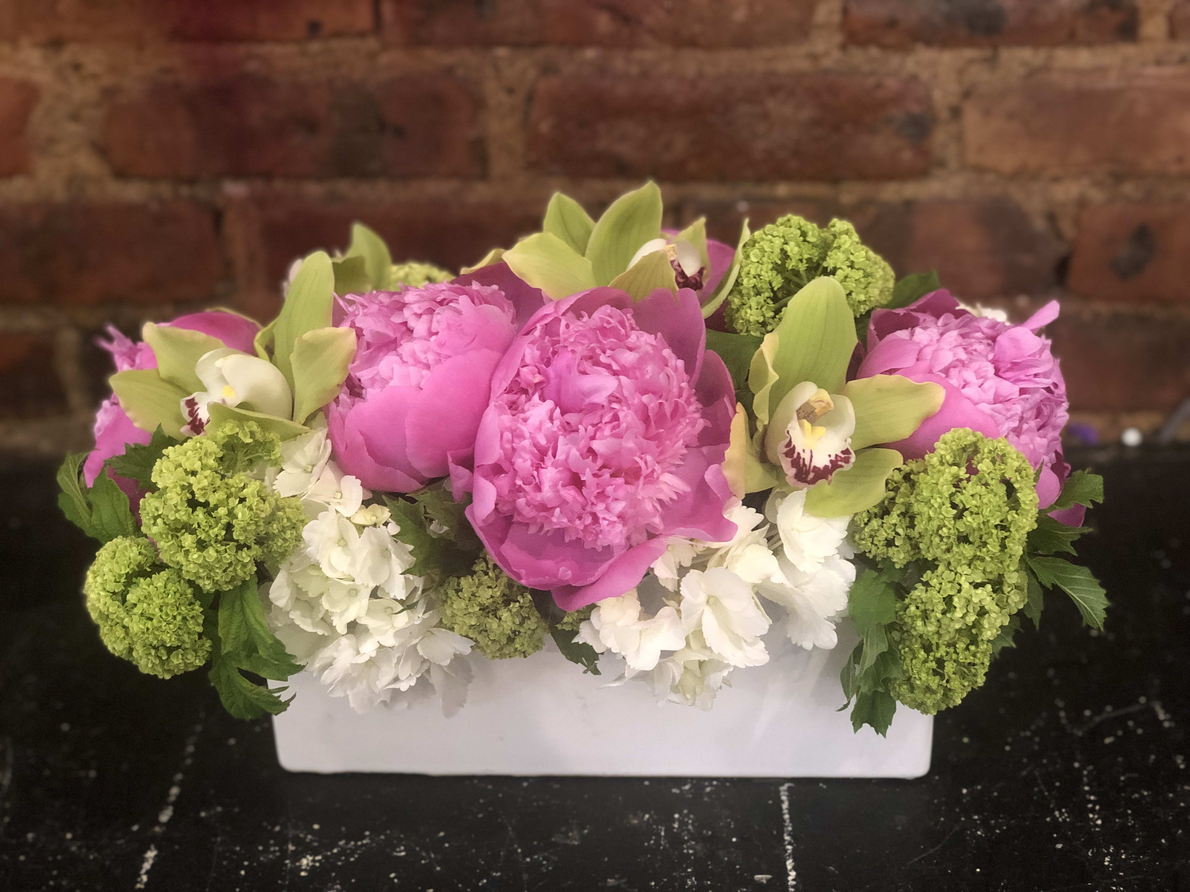 Pink peonies and green orchids in a white rectangular vase