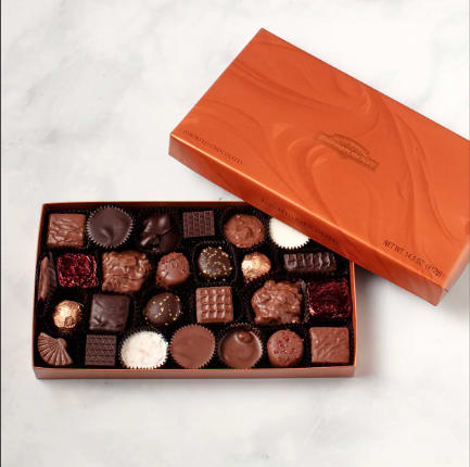 Open box of assorted chocolates with orange lid