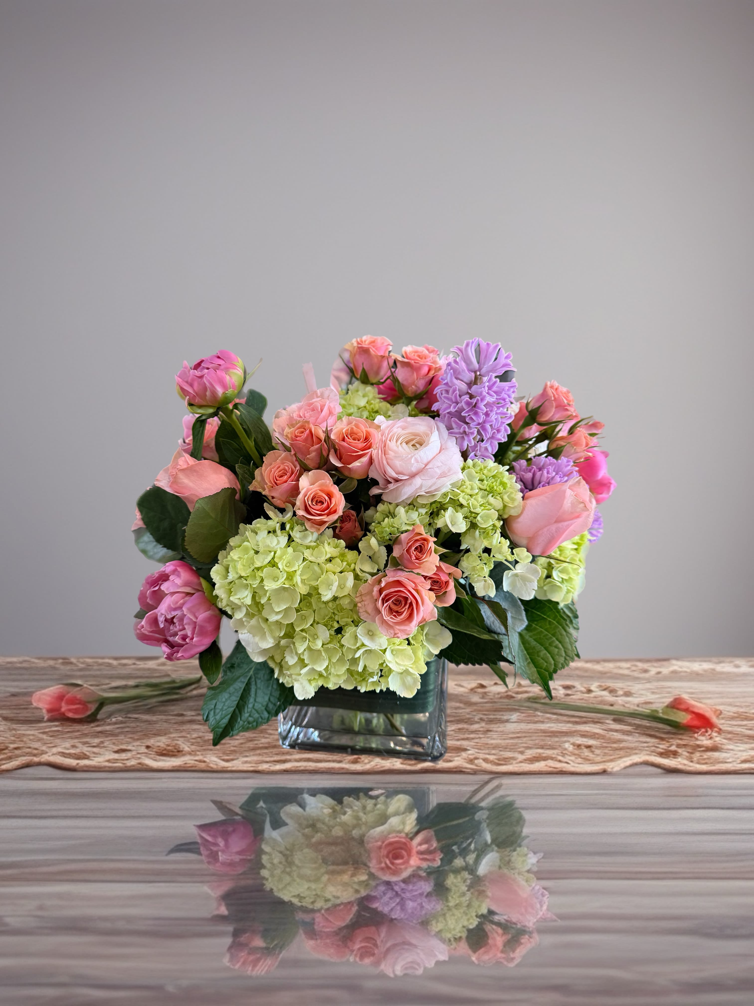 Pink and lavender flowers arranged in a square glass vase