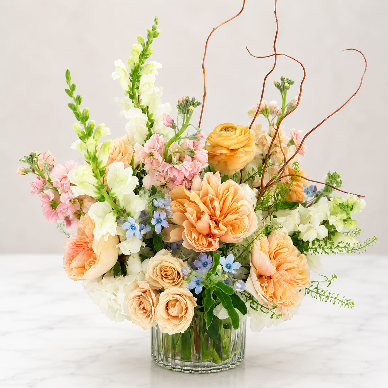 Parisian Stroll  - Experience the beauty of a Parisian Stroll with our stunning floral arrangement. This exquisite bouquet features a mix of roses, ranunculus, snapdragons, and stock elegantly designed in a glass vase. Bring a touch of Parisian charm to any space with this enchanting arrangement. Order now and elevate your decor with the beauty of fresh flowers.  Orientation: All-Around All prices in USD ($) Standard, DELUXE (SHOWN), Premium