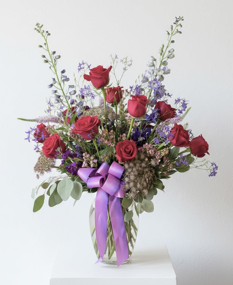 Jessica  - A tall beautiful vase arrangement of red roses, purple delphinium and Queen Anne’s Lace. An upgraded and romantic twist to a dozen roses. 