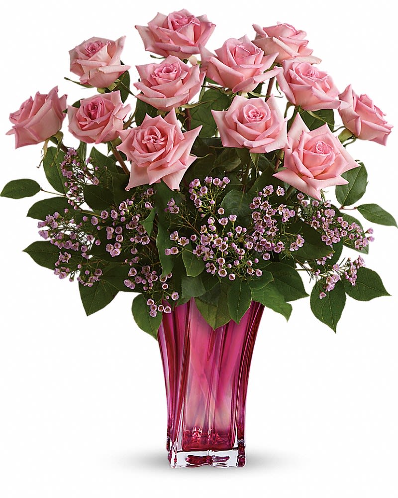 Pink roses in a tall magenta glass vase with small purple filler flowers