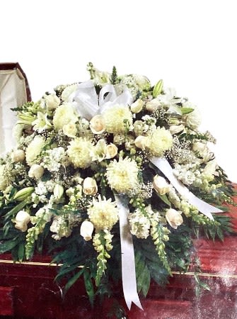 Large white funeral spray with lilies and ribbon on a stand
