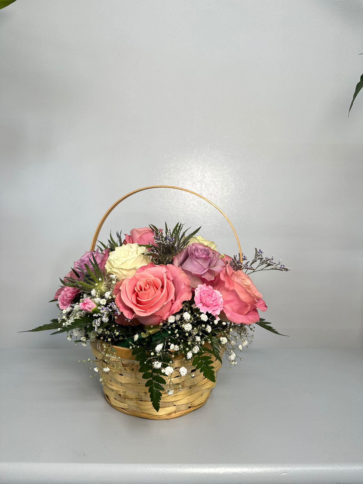 Basket of pink, cream, and lavender roses with baby's breath