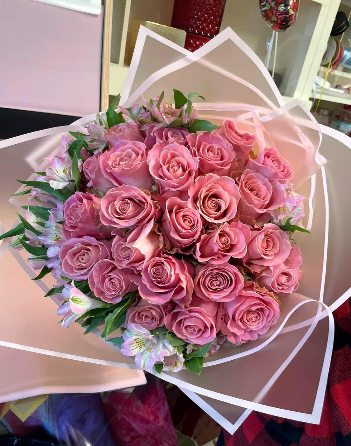 Bouquet of pink roses with small pale lilies wrapped in blush paper