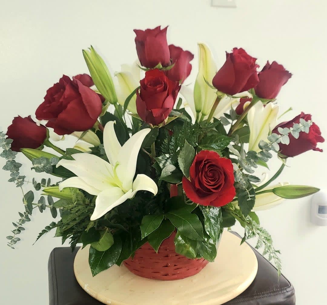 Red roses and white lilies in a red basket arrangement