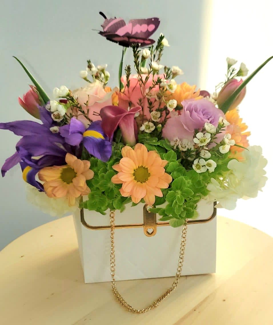Colorful flower arrangement in a white handbag-shaped container