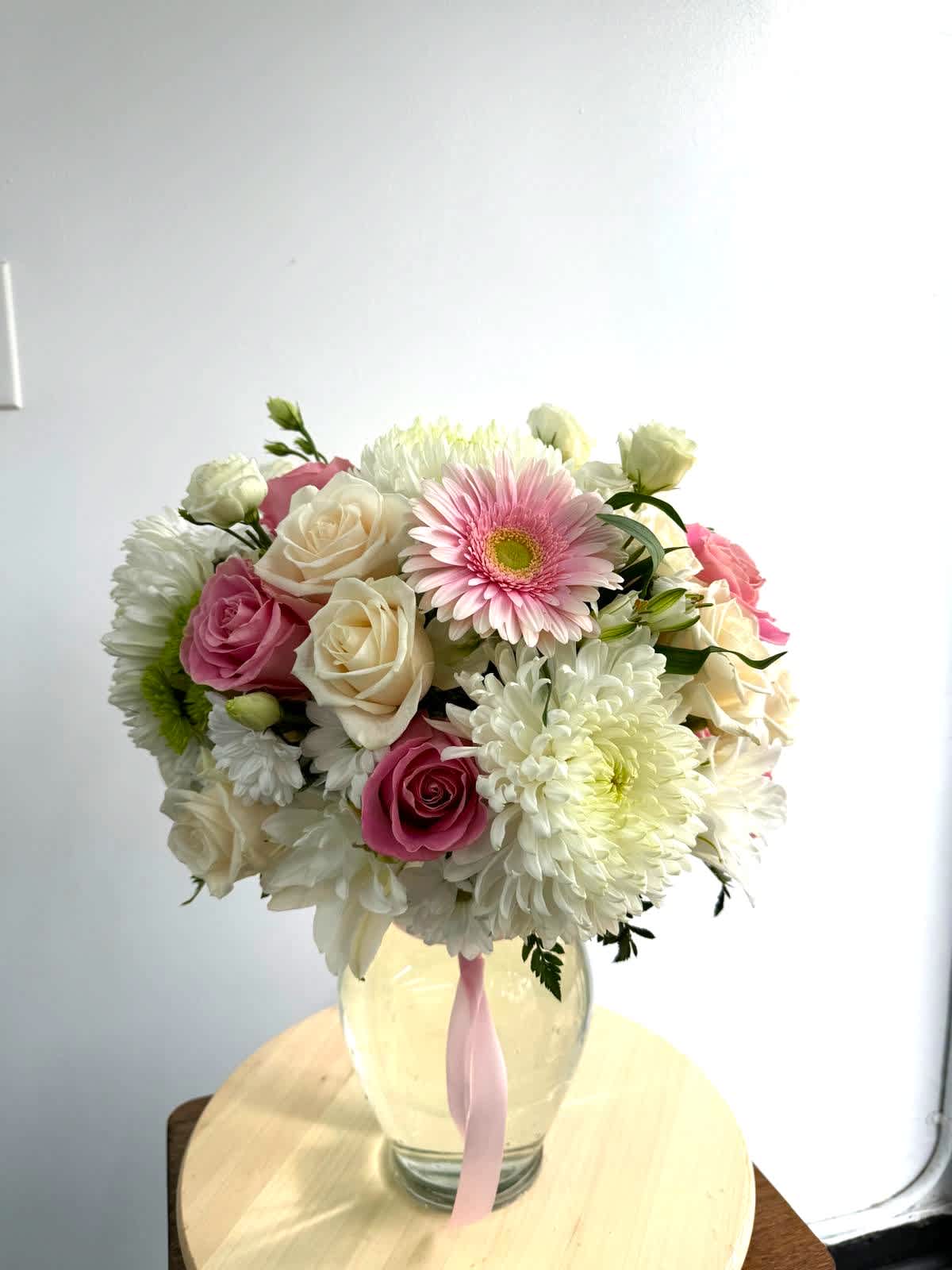 Pink and white mixed bouquet in a glass vase with a pink ribbon