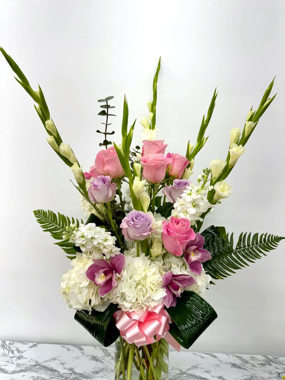 Pink and lavender roses with white flowers in a glass vase