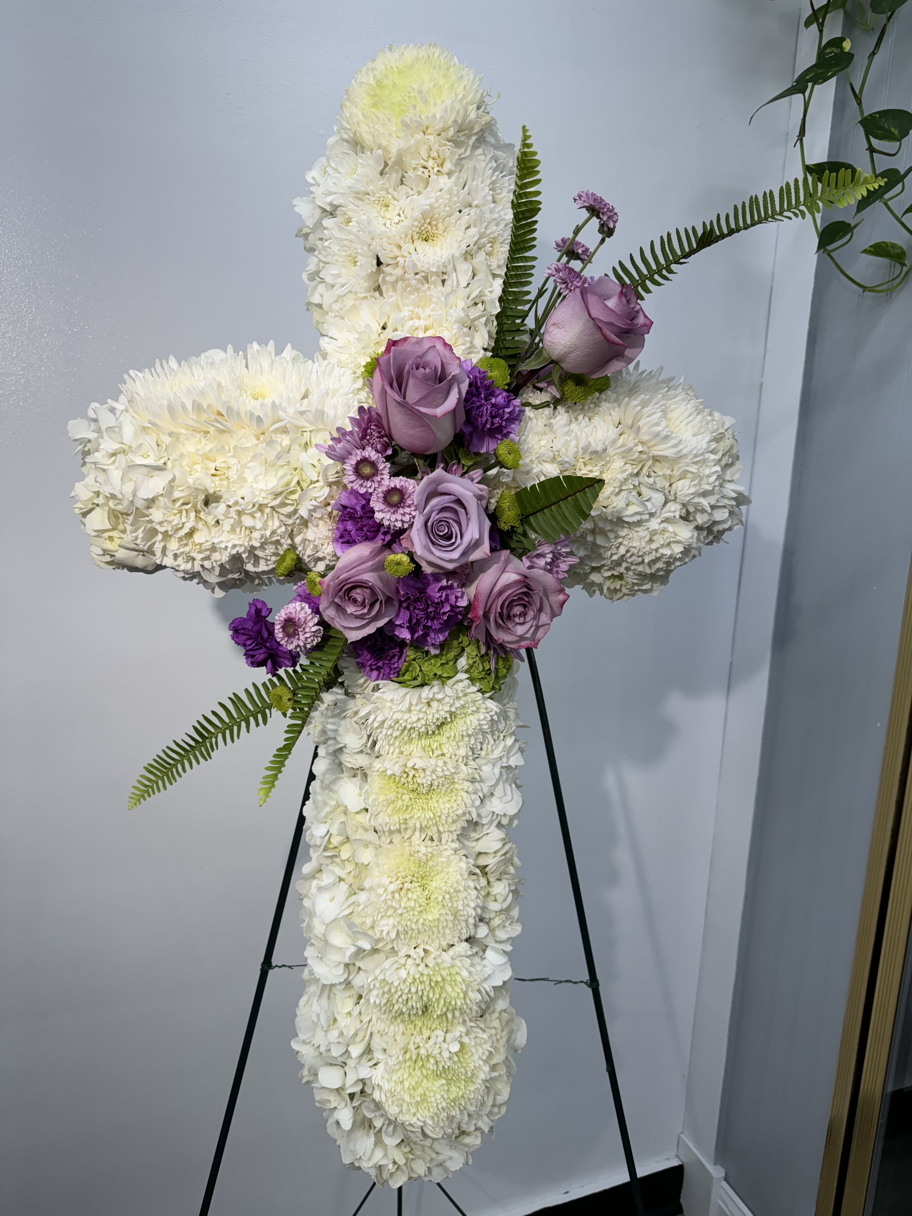 Standing floral cross with white blooms and lavender roses