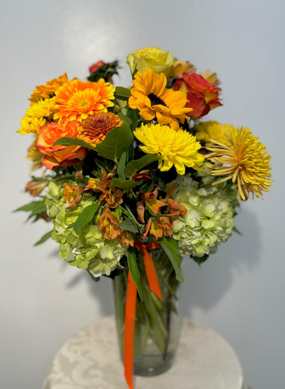 Mixed bouquet of yellow, orange, and red flowers in a glass vase
