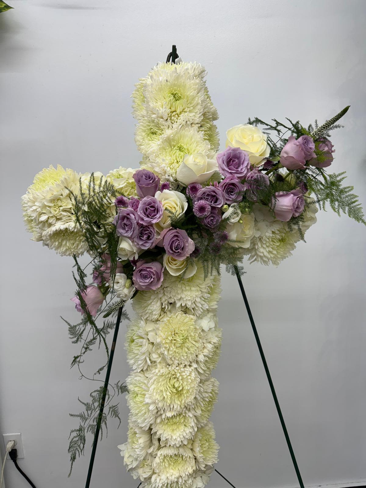 Cross-shaped floral tribute with white chrysanthemums and lavender roses