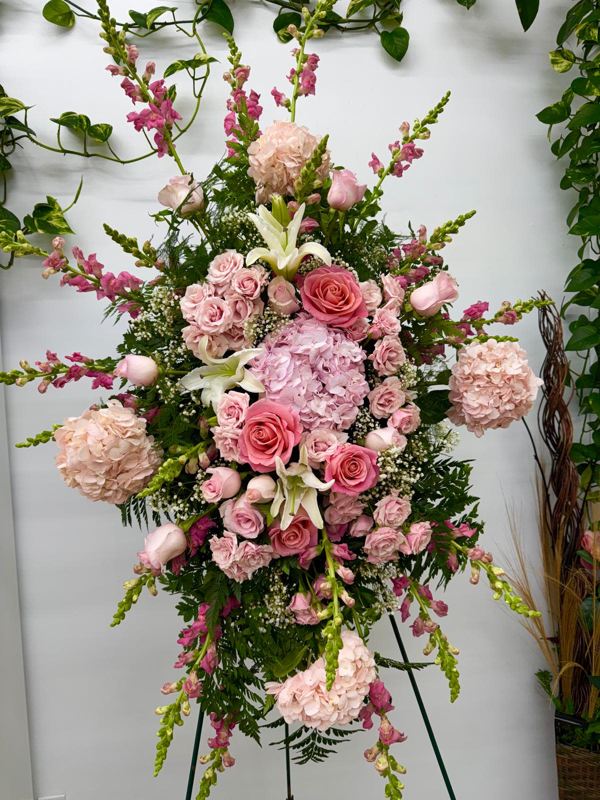Tall pink floral standing arrangement with roses, hydrangeas, lilies, and snapdragons